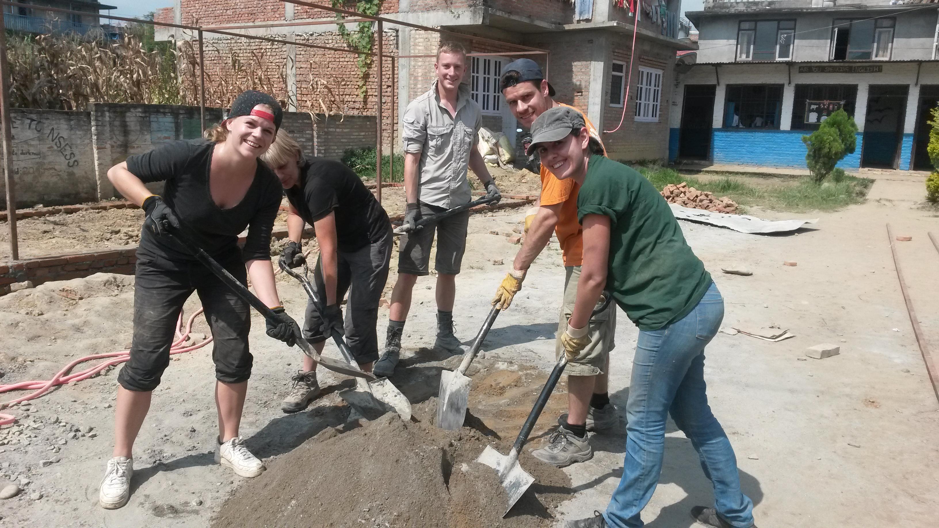 Projects Abroad high school student volunteers doing construction work in Nepal dig up sand. High school student volunteers doing building work in Nepal dig up sand needed for building work.